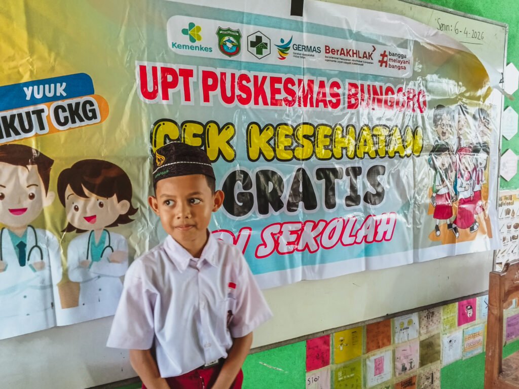 Seorang siswa SD IT Abu Bakr Ash Shiddiq berdiri di depan spanduk pelaksanaan CKG di Sekolah